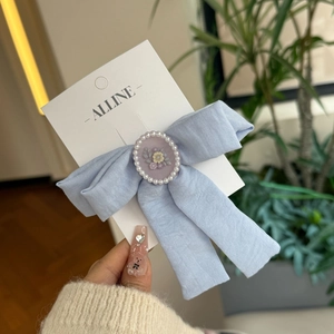 Close-up of light blue floral bow hair clip with pearl-rimmed floral cameo detail