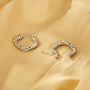 Silver twisted rope hoop earrings in vintage stainless steel on gold satin background