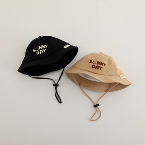 Macro shot of cotton kids bucket hats with Sunny Day smile embroidery and chin straps