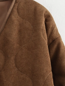 Detailopname van bruine corduroy gewatteerde jas met textuur en ronde stiksels