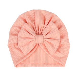 Flat lay of pink ribbed cotton baby turban hat featuring a large decorative bow detail