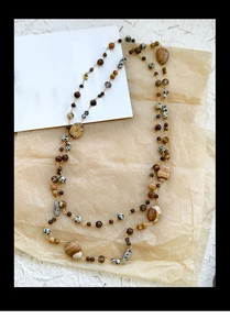 Detailed macro view of 14K gold plated chain with brown and white natural stone beads