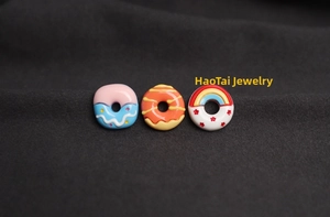 Macro shot of three 3D resin donut charms with colorful patterns on gray fabric texture