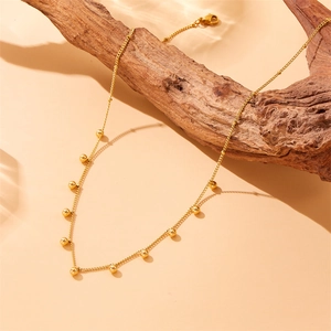 French retro gold bead necklace in stainless steel displayed on a rustic wood piece