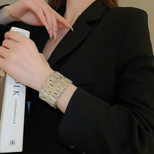 Close-up of a silver braided metal cuff bracelet worn by a model in a black blazer
