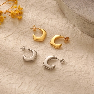 Minimalist 18K gold and silver stainless steel C-shaped geometric earrings on textured background