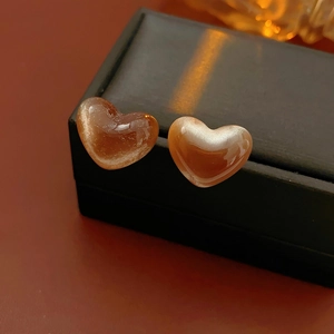 Gros plan de boucles d'oreilles en résine ambre en forme de cœur sur une boîte noire