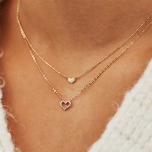 Close-up of double-layer gold necklace featuring solid and sparkling pavé heart pendants