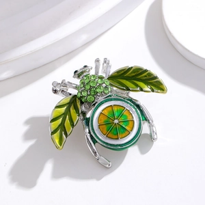 Vue macro de broche insecte argentée avec cristaux verts et aile en tranche de citron
