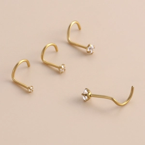 Close-up of four gold stainless steel nose studs with sparkling cubic zirconia crystals