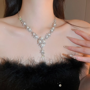 Close-up of elegant silver Y-shaped necklace with pearls and rhinestones on a model
