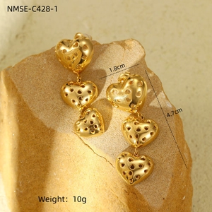 Detail view of gold triple heart dangle earrings on rock with size and weight specs