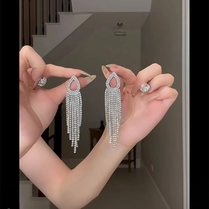 Close-up of silver rhinestone tassel earrings with teardrop tops and sparkling crystal chains