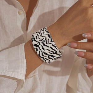 Macro shot of stylish wide zebra print bangle on woman wearing a white shirt