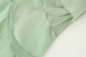 Detail von hellgrünen Rüschenkanten mit feinen Nähten am Chiffon-Langarmkleid