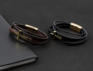 Detail of layered leather bracelets with golden cross charms and magnetic clasps