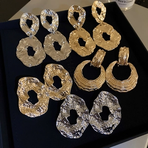 Detail view of 5 pairs of geometric gold and silver earrings with hammered metal texture