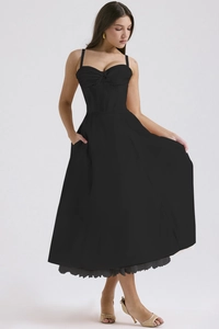Detail of black corset dress featuring lace hem, ribbon lacing, and functional pockets