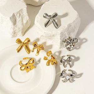 Macro detail of gold and silver bow-shaped rings with pearl accents on a white stone