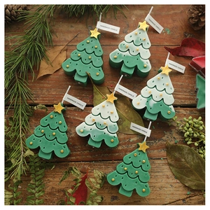 Top view of handmade Christmas tree scented candles with gold stars on a wooden desk