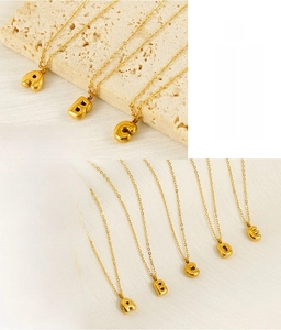 Detailed macro view of gold bubble alphabet pendants showing polished 3D metal finish