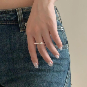 Minimalist 925 sterling silver knotted cross ring worn on model finger with blue denim