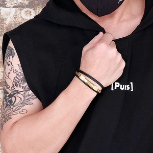 Detail of men's black braided leather bracelet with polished gold stainless steel chain