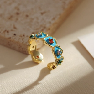 Macro view of golden irregular ring featuring blue enamel and multicolor gemstones