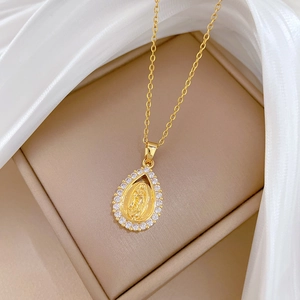 Detailed macro of gold teardrop pendant featuring religious portrait and sparkling crystals