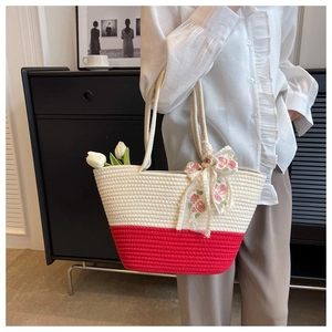 Detail of woven straw tote bag featuring a pink floral lace bow on the textured surface