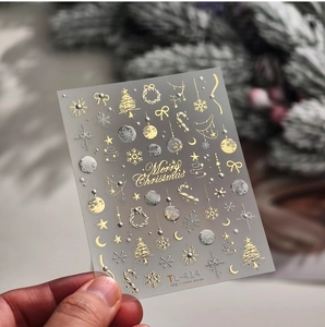Makroaufnahme von 3D-Weihnachtsnagelaufklebern mit goldenen Schneeflocken und Rentieren