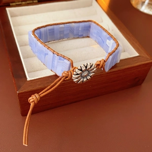 Dettaglio del bracciale boho con pietre azzurre, cordino in cuoio e fibbia floreale
