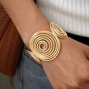 Macro shot of gold spiral swirl cuff bracelet on wrist showing metallic luster