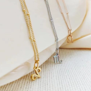 Detailed view of gold, silver, and rose gold zodiac pendants on a beige silk background