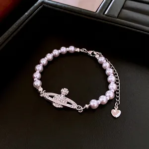 Elegant pink pearl Saturn orb bracelet with silver crystal accents on black background