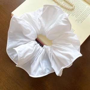 Gros plan d'un chouchou géant blanc en tissu plissé doux sur une table en bois naturel