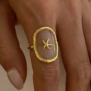 Minimalist gold starfish ring with hammered texture worn on hand in a macro view