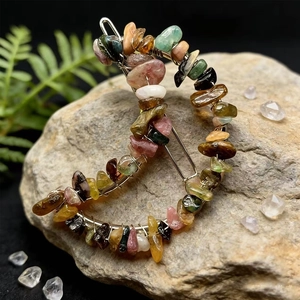 Detailed macro shot of a crescent moon hair clip with colorful natural crystal stones