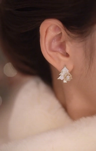 Close-up of sparkling Christmas tree and snowflake earrings with micro-set zircons on model