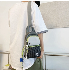 Detail view of water-resistant gray crossbody chest bag with neon green piping on model