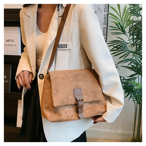 Detail view of the brown matte suede texture and metal buckle on this vintage shoulder bag