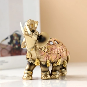 Elegant gold resin elephant figurine with decorative pink saddle and upward trunk