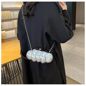 Borsa da sera argentata ondulata con tracolla a catena su cappotto nero