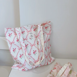 Detail of floral tote bag showing pink bows and red roses pattern with woven label