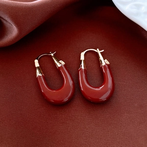 Detail of vintage French red U-shaped earrings with gold plating on red silk fabric