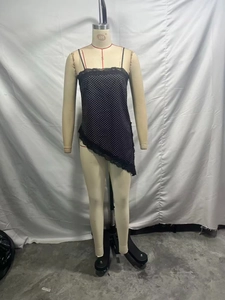 Detailed close-up of a black polka dot camisole with lace trim and asymmetrical hemline
