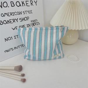 Close-up of blue and white striped canvas pouch with silver zipper and woven label