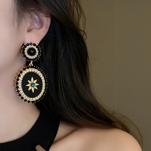Detailed view of vintage gold and black earrings with celestial sun and star motifs