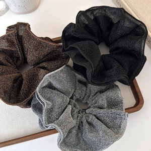 Detailed view of layered lace scrunchies in brown, black and silver with metallic luster