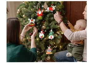 Familie dekoriert Weihnachtsbaum mit Holzanhängern wie Weihnachtsmann und Schneemann